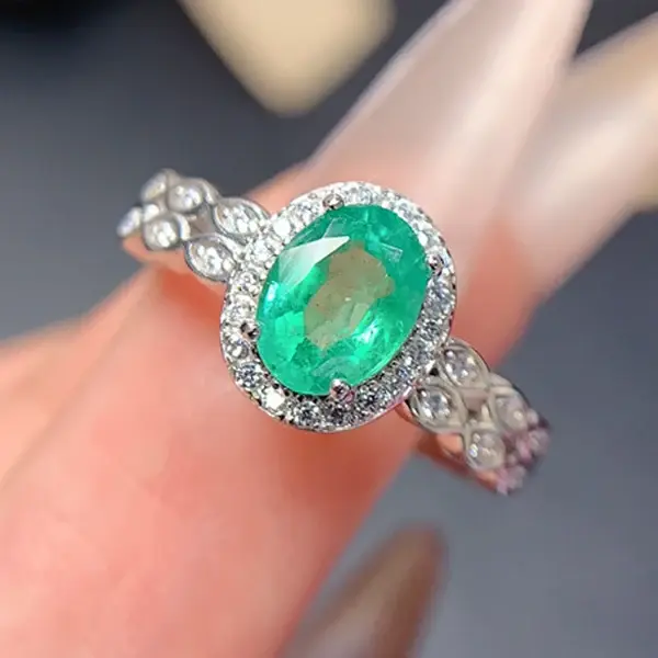 Oval natural emerald and diamond halo engagement ring